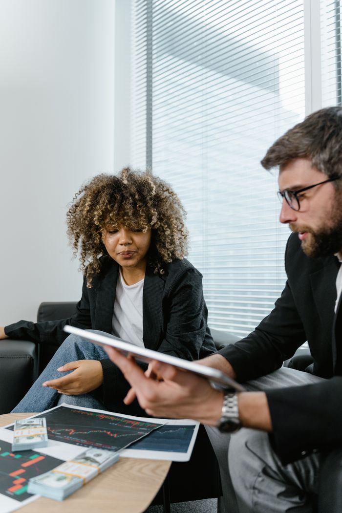 Offerings Two professionals discussing financial graphs on a tablet in a modern office setting.